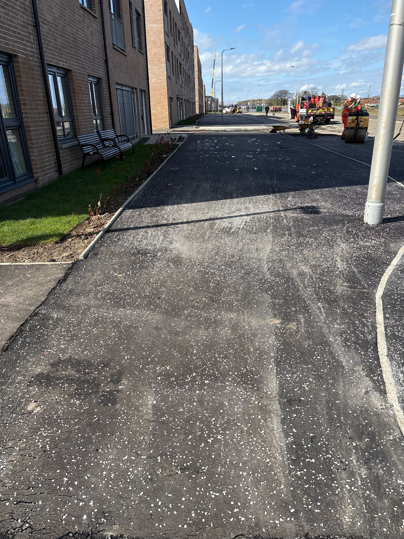 New asphalt footway adjacent to residential properties during final compaction and finishing works