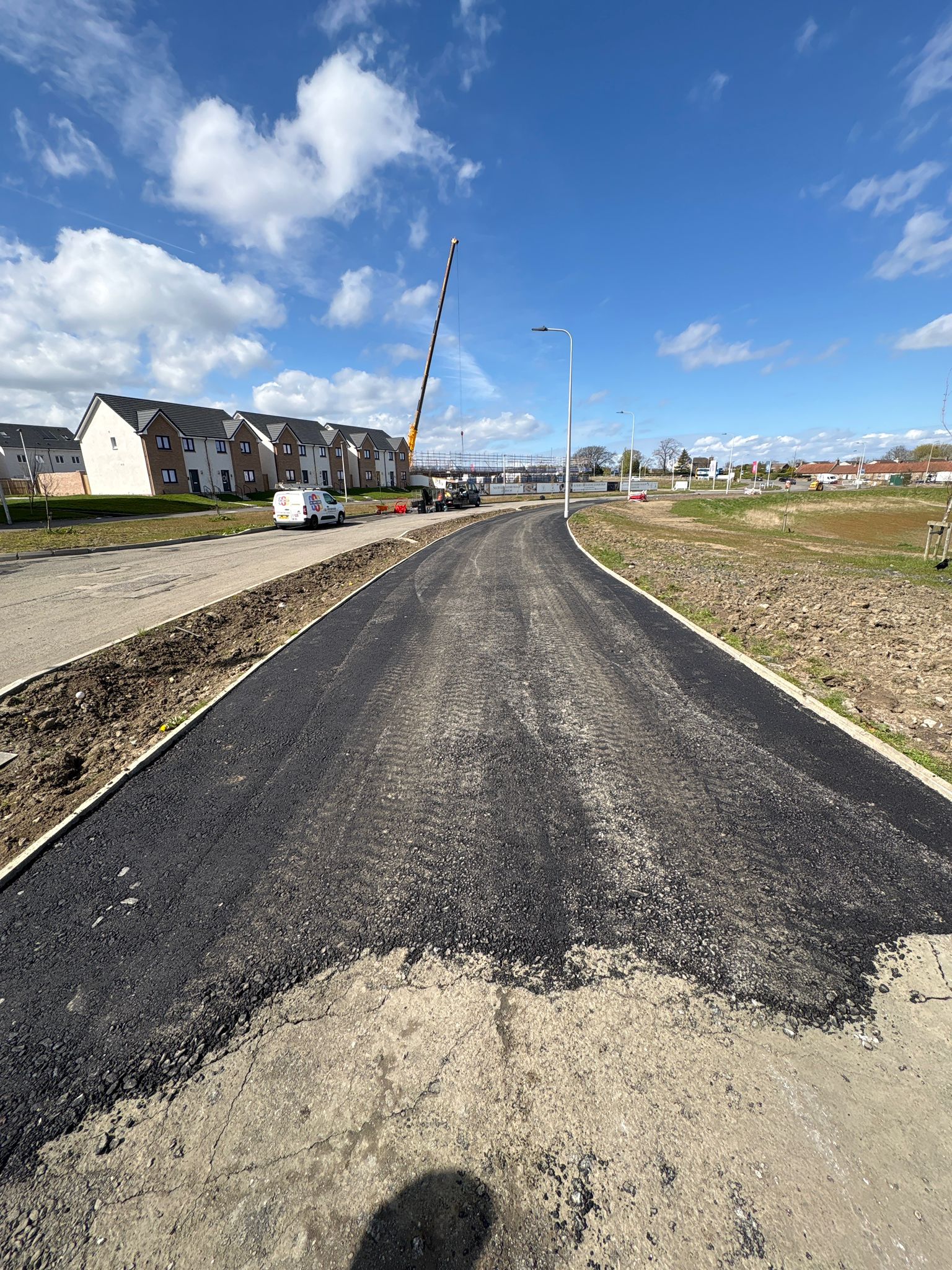 Curved roadway with fresh asphalt surfacing integrated into the wider development layout